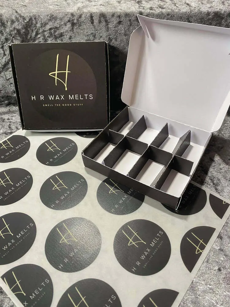 Open black 8-cell wax melt box with card dividers on printed logo paper