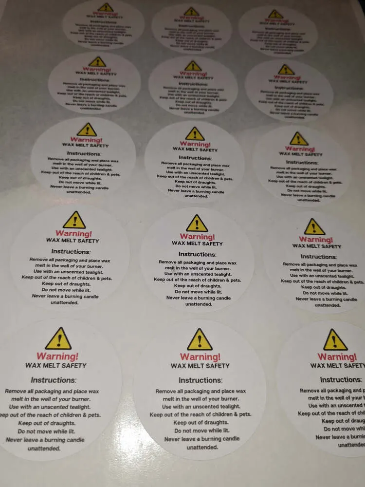 Close view of round wax melt warning stickers on a white backing sheet